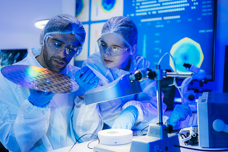 Technician inspecting a wafer in a semiconductor cleanroom